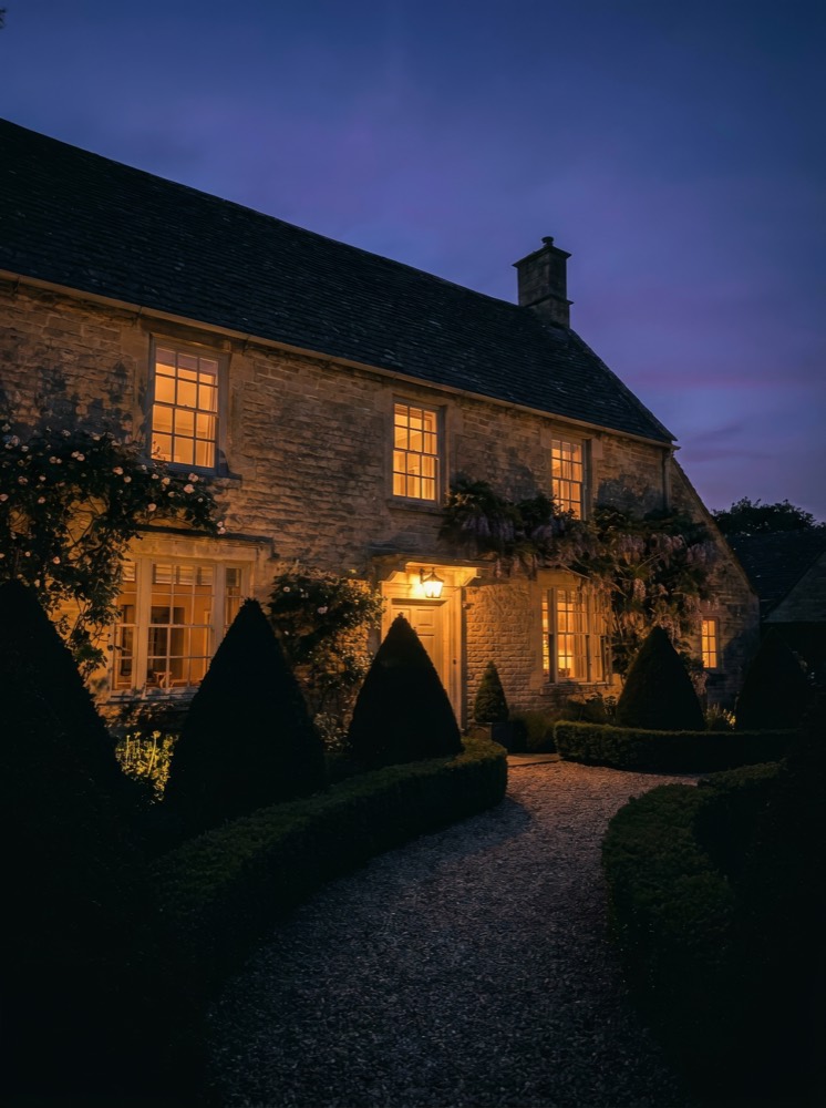 Cotswold stone home at dusk, listed by Bramble & Co